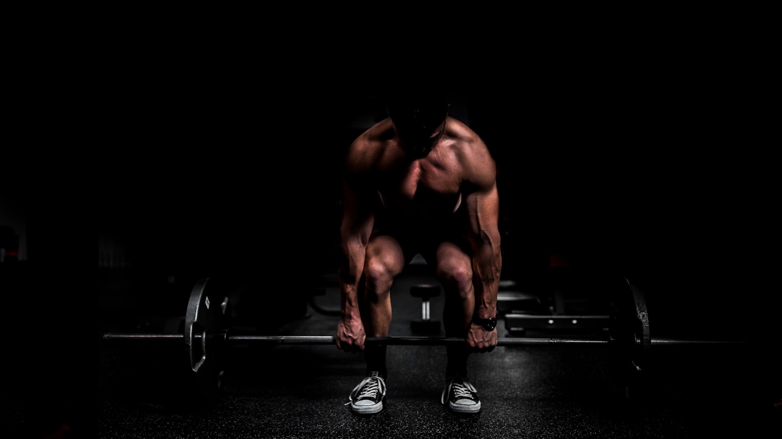 A lifter set up over a loaded barbell on the Iron Republic platform, lit from behind in a darkened gym