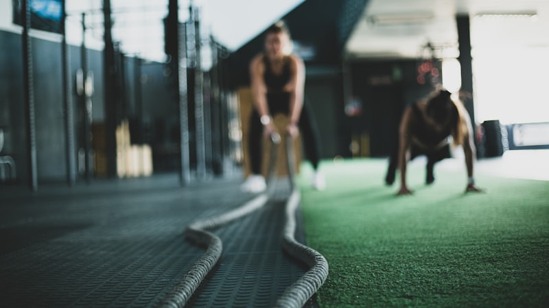Two athletes working battle ropes during a conditioning circuit