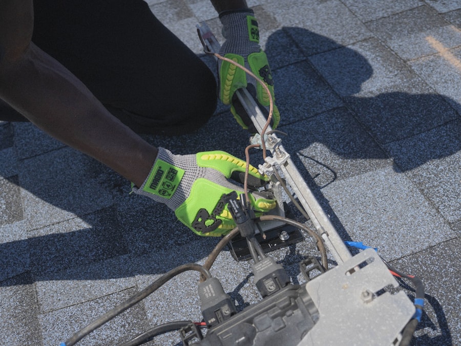 Close-up of gloved hands connecting MC4 cables to a rail-mounted microinverter on a shingled roof